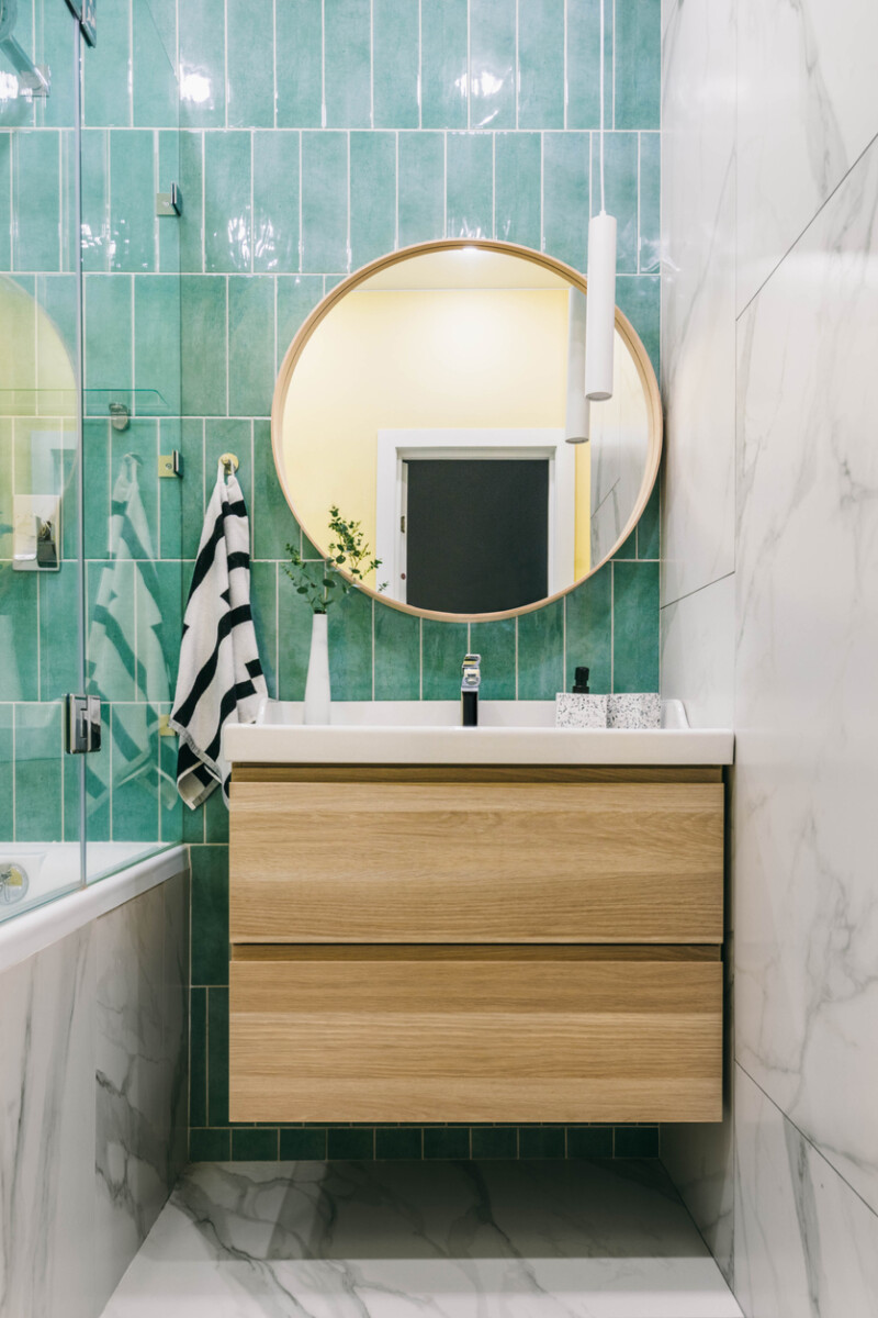 Stylish bathroom with marble and green tiles, featuring a modern washbasin and minimalist decor.