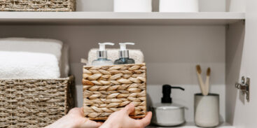 Woman puts wicker box with cosmetics products in bathroom closet