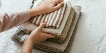 Woman folding clothes in a bedroom, organising laundry in boxes and baskets.