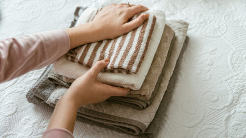 Woman folding clothes in a bedroom, organising laundry in boxes and baskets.