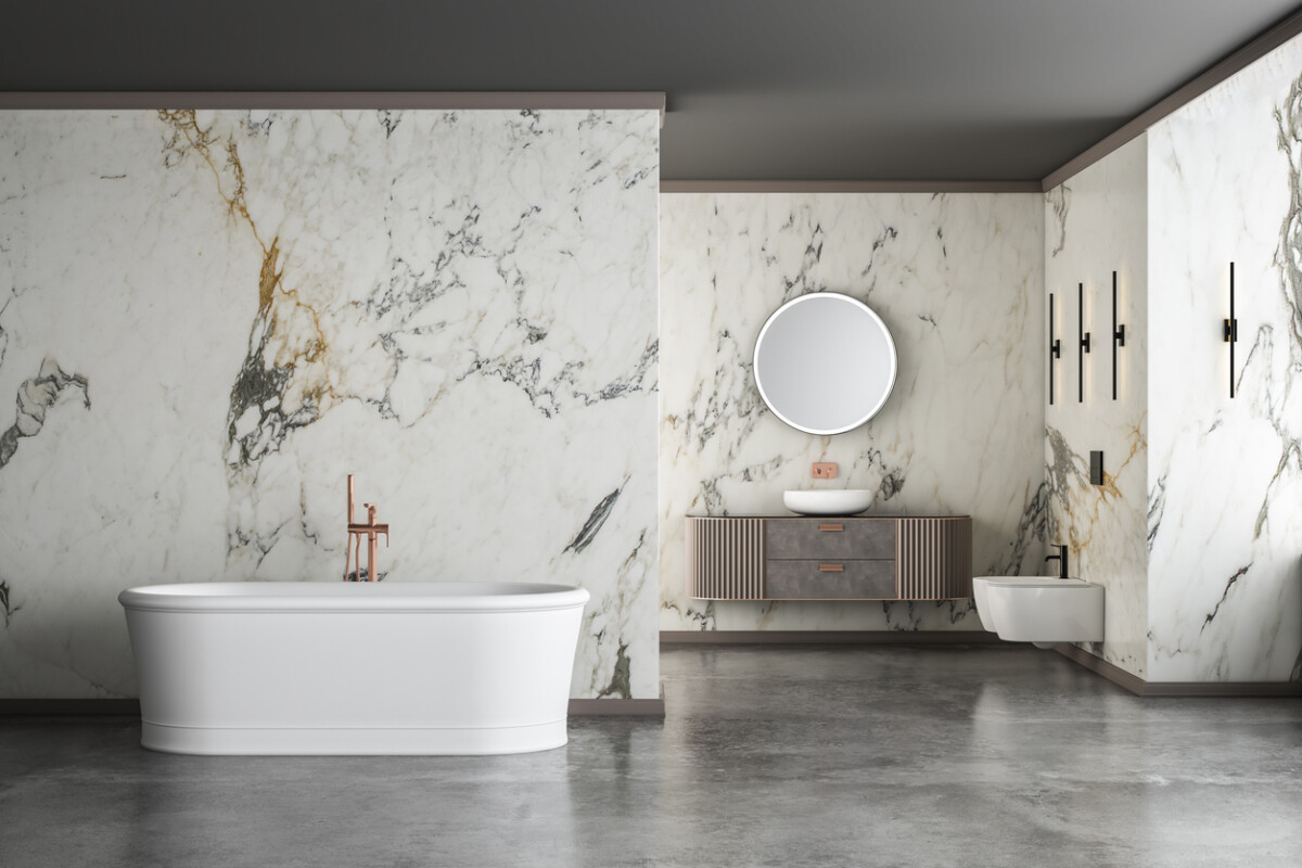 Modern luxury bathroom with white marble walls, freestanding bathtub, concrete floor, and indoor plants.