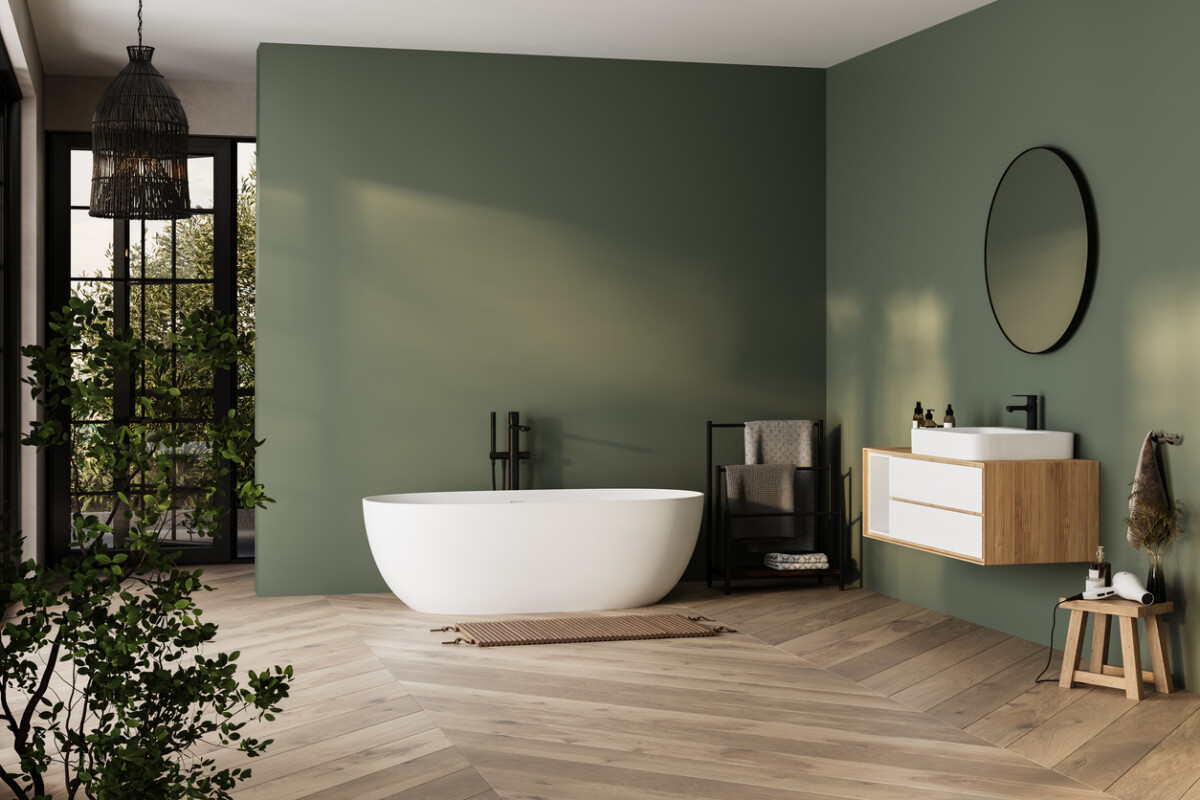 Modern green minimalist bathroom interior with a freestanding bathtub, bathroom cabinet, and white sink, featuring clean lines and neutral colours